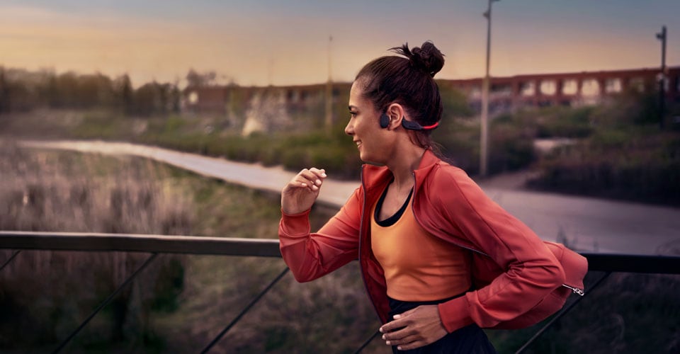 Atleta usando auriculares de conducción ósea en una carrera al aire libre